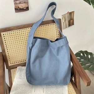 Texture dettagliata di una borsa tote in tela blu su una sedia in rattan vintage per uso quotidiano