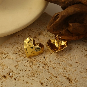 Vintage goldene Herz-Ohrstecker mit gehämmerter Metallstruktur auf Naturstein