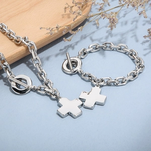 Detailed view of silver cross pendant and OT buckle on coarse chain necklace set