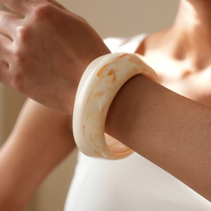 Close-up of wide resin bangle with amber patterns and stylish marbled texture on wrist