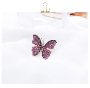 Detailed close-up of a butterfly brooch with purple and black rhinestones on gold metal
