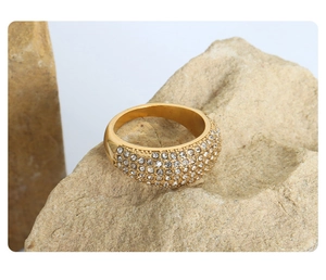 Close-up of gold-plated titanium ring with pavé-set crystals on natural rock background