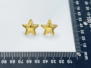 Detail shot of golden star stud earrings with textured surface and measurement scale