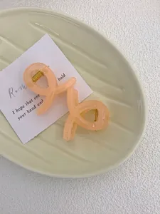 Detail of two beige acrylic hair claws with gold springs in a ceramic tray