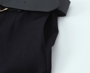 Detail of black pants side pocket featuring a leather belt with golden metal buckle