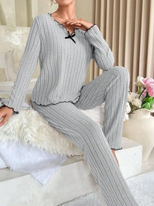 Detail of ribbed gray lounge set showing the V-neck with bow and black ruffle edge