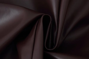 Detail shot of premium deep burgundy faux leather texture and soft material folds