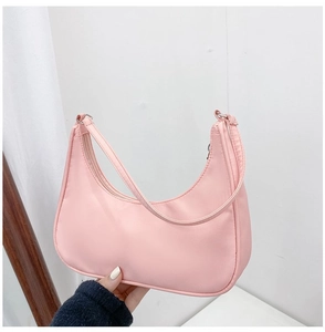 Close-up of pink nylon crescent underarm bag held by hand, showing smooth fabric texture