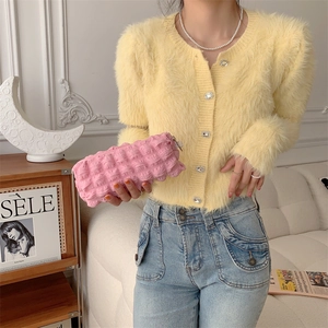 Yellow fuzzy cardigan with rhinestone buttons and a pink bubble texture clutch bag
