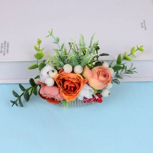 Detailed shot of handmade bridal hair comb with realistic orange and pink roses and green leaves