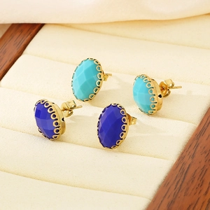 Detail of vintage oval blue glass earrings in gold claw settings on beige velvet
