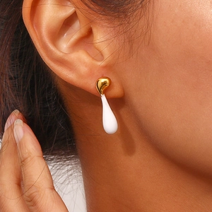 Macro view of asymmetrical molten lava earrings in gold and white on a model