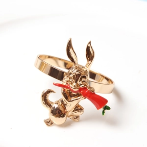 Macro view of a golden bunny napkin ring holding a red carrot with green leaf details