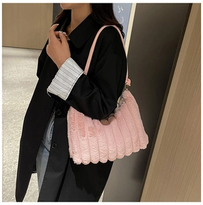 Dettaglio della borsa a spalla in ecopelliccia rosa con trama ondulata e finiture dorate