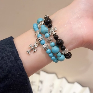 Gros plan de bracelets de perles turquoise et noirs avec pendentifs croix en argent