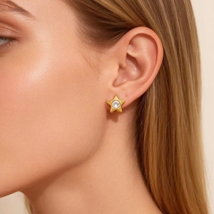Eleganter goldener Stern-Ohrstecker mit hellem Kristall am Ohr des Models