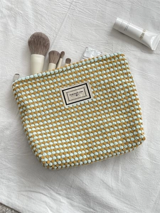 Detail of blue and yellow checkered woven cosmetic bag showing texture and labels