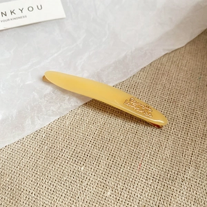 Dettaglio del fermaglio in resina ambra con incisione Barrette La France e clip oro