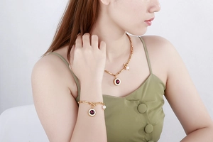 Detail of gold jewelry set with wine red gemstones, Roman numerals and pearls on model