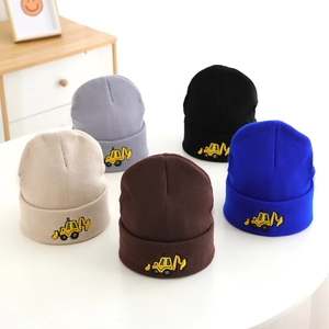 Close-up of five knitted toddler hats featuring detailed yellow excavator embroidery details