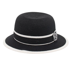 Detailed view of black straw sun hat with white brim and pearl camellia flower ornament