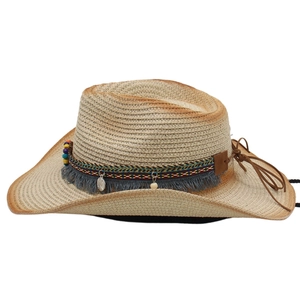 Detail of straw cowboy hat with ethnic band, colorful beads, and silver pendants
