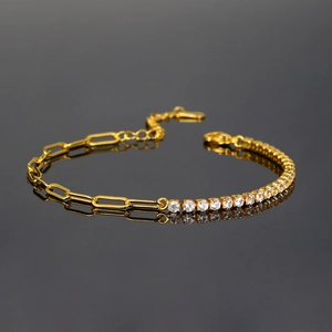 Macro shot of gold paperclip chain bracelet with round white zirconia in mirror reflection