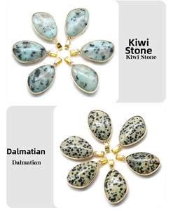 Close-up of teardrop-shaped kiwi stone and dalmatian stone pendants with gold trim