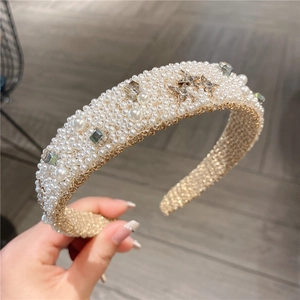 Close-up of wide thick headband with white pearls and sparkling star rhinestones