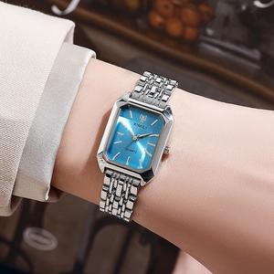 Elegant silver square watch with blue dial on woman wrist in a cozy cafe setting