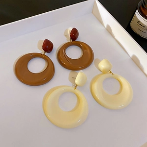 Vue détaillée de boucles d'oreilles géométriques en acrylique café et crème sur un plateau
