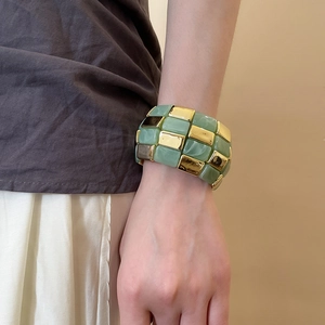 Detail of wide geometric bracelet with green stone marble blocks and gold metal pieces