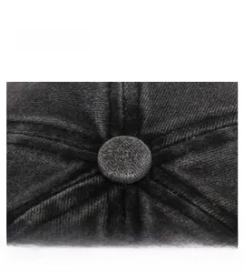 Macro shot of the top button and reinforced stitching on a black washed cotton cap