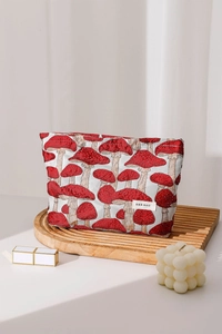 Detail of red mushroom jacquard makeup bag on wooden tray with beauty accessories