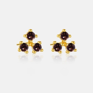 Macro detail of gold earrings with three purple zircon gemstones in a triangular layout