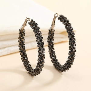 Macro detail of hoop earrings featuring high-density black rhinestones and bronze metal base