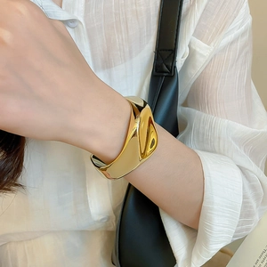 Detailed view of an organic twisted chunky gold open bangle on a model's wrist
