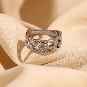 Detailed macro view of silver chain ring with white rhinestones on soft fabric