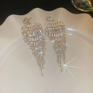 Detail of silver tassel earrings with zircon flower studs on a white ceramic plate