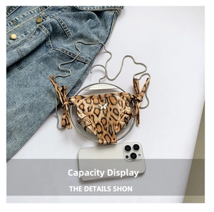 Mini leopard print shoulder bag with metal butterfly and chain next to a phone