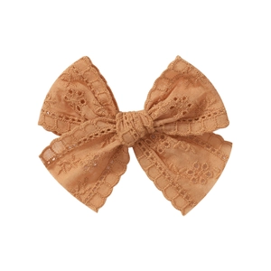 Close-up of mustard yellow lace bow hair clip with vintage hollow embroidery detail