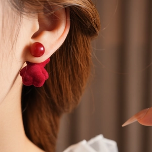 Close-up of a model wearing red flocked bear earrings with a glossy red spherical top