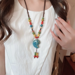 Dettaglio del ciondolo a conchiglia in ceramica su una collana di perline colorate