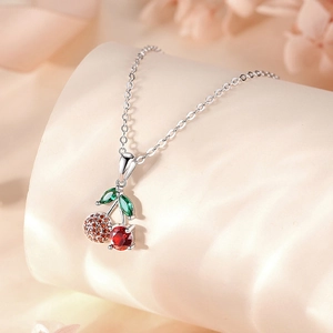 S925 sterling silver cherry pendant necklace with red and green gemstones on silk background