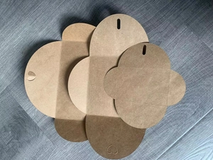Flat lay of unfolded kraft paper boxes with heart-shaped clasps and natural wood grain texture