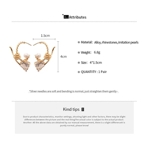 Detail view of heart-shaped gold earrings with faux pearl and crystal pendant with dimensions