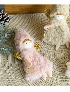 Detail view of plush Christmas angel ornaments with gold wings on a woven mat