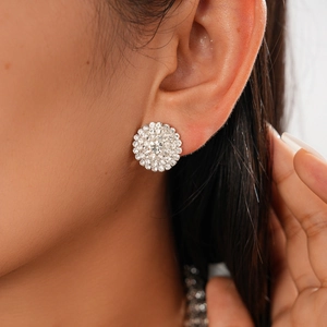 Close-up of sparkling diamond-encrusted silver circular stud earrings worn by a model