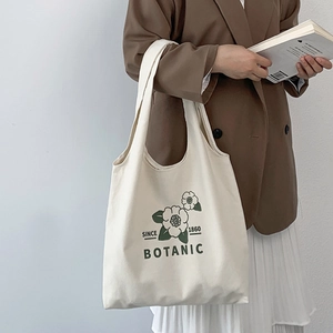 Close-up of cream canvas tote bag featuring green floral print and wide shoulder strap