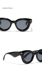 Detail view of black cat-eye sunglasses with golden diamond-shaped rivets on temples